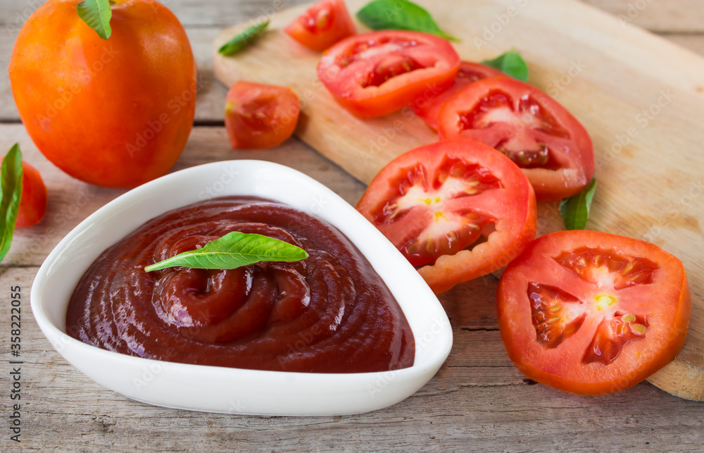 close-up bowl of ketchup or tomato sauce and fresh tomatoes on Wooden table. close-up bowl of ketchup or tomato sauce and fresh tomatoes on Wooden table.