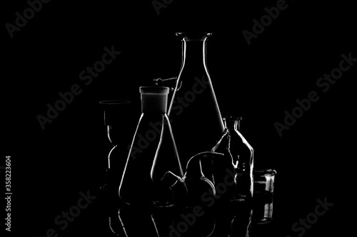 Low-key Studio Shot of a White silhouette of a chemical laboratory utensils light glasses isolated on a black Background. Smooth lines and shapes. .