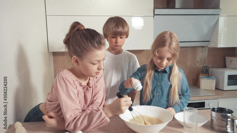Children prepare dough for pie, cookies. Add salt to the dough. Mix with a whisk Children prepare dough for pie, cookies. Add salt to the dough. Mix with a whisk