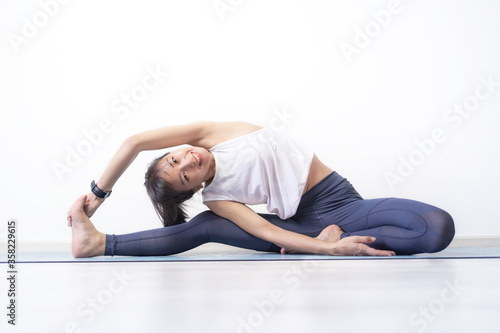 Portrait of young sporty Asian woman warm up exercise work out sitting on Yoga mat at home, A woman with smiley face stretching, healthy quarantine concept