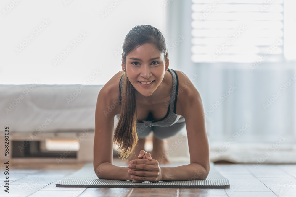 Obraz premium Attractive Asian woman practice yoga Plank pose at home