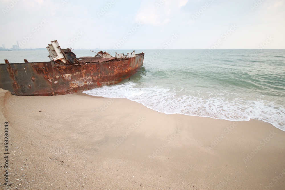Old rusty fishing boats on the sandy beach near the sea.