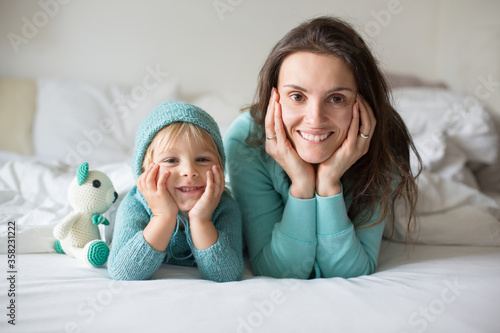 Fotografia Happy mother and child, boy, with matching outfit, lying in bed, smiling happily