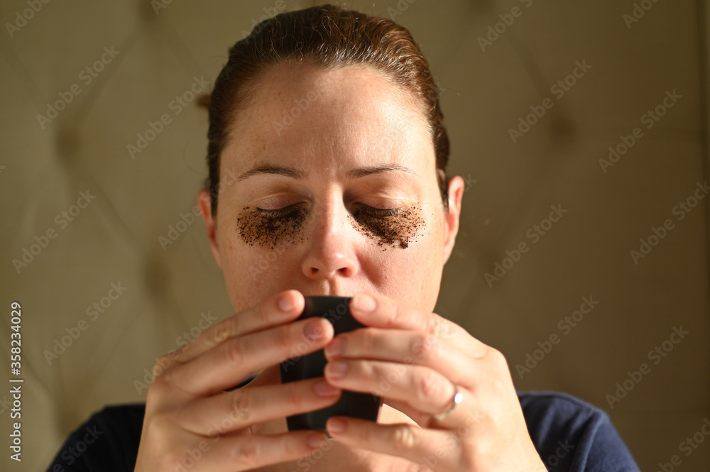 Woman relaxing at home with coffee grounds on her face Woman relaxing at home with coffee grounds on her face
