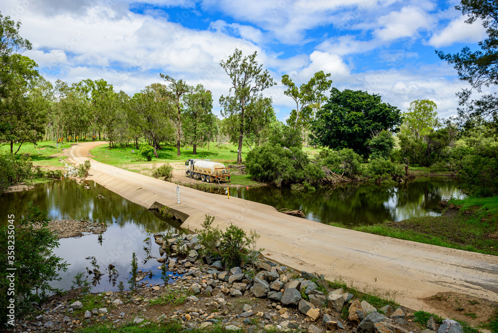 Concrete floodway on Tableland Road with truck pumping water from a creek, Queensland