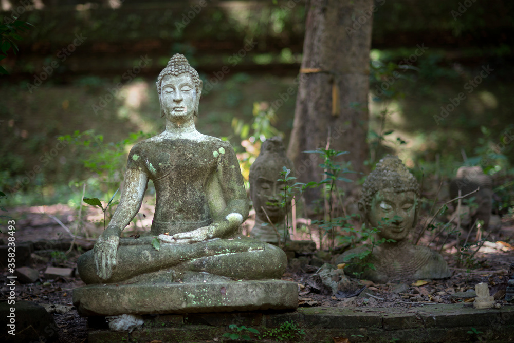 Ancient old damaged Buddha statue sculpture of stone were left statue in the forest ruin temple of Thailand