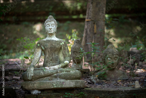 Ancient old damaged Buddha statue sculpture of stone were left statue in the forest ruin temple of Thailand
