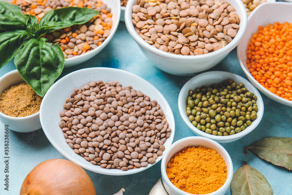 Bowls with lentils and spices on color background Bowls with lentils and spices on color background