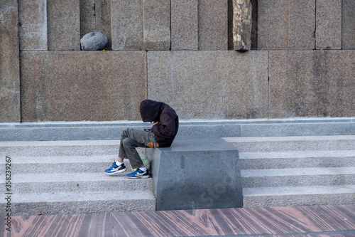Photography A young lonely boy in the park checking his mobile phone
