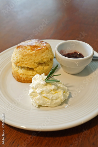 Close up butter scone with berries jam and clotted curd cream served on wooden table
