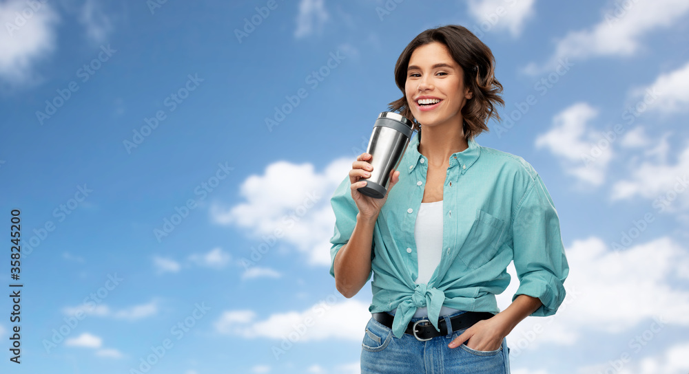 people concept - portrait of happy woman in turquoise shirt drinking from thermo cup or tumbler for hot drinks over blue sky and clouds background people concept - portrait of happy woman in turquoise shirt drinking from thermo cup or tumbler for hot drinks over blue sky and clouds background
