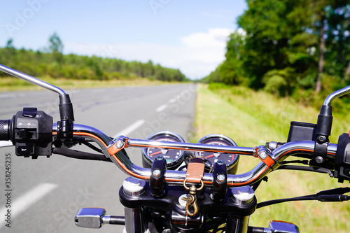 motorbike chrome handlebars of classic vintage motorcycle parked in a road in summer countryside