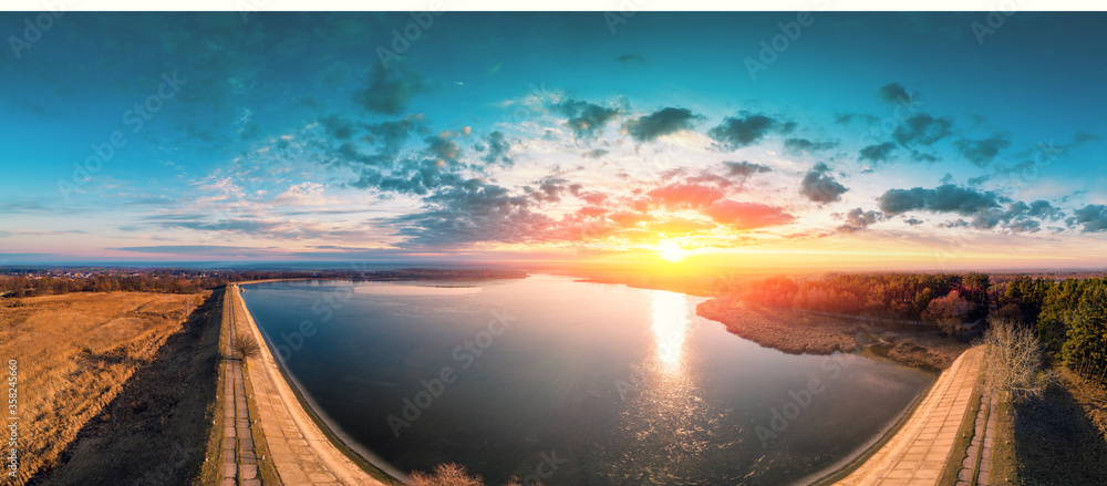 Sunrise over lake in early spring. Serene lake in the morning. Nature landscape. Dam on the lake. View from above. Panorama - obrazy, fototapety, plakaty 