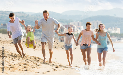 Family with four children runnin on beach on weekend