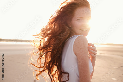 Fotografie, Obraz Beautiful young lady with long healthy red hair and cute dress