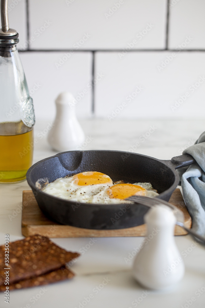 fried eggs in a cast-iron skillet on white marble table fried eggs in a cast-iron skillet on white marble table