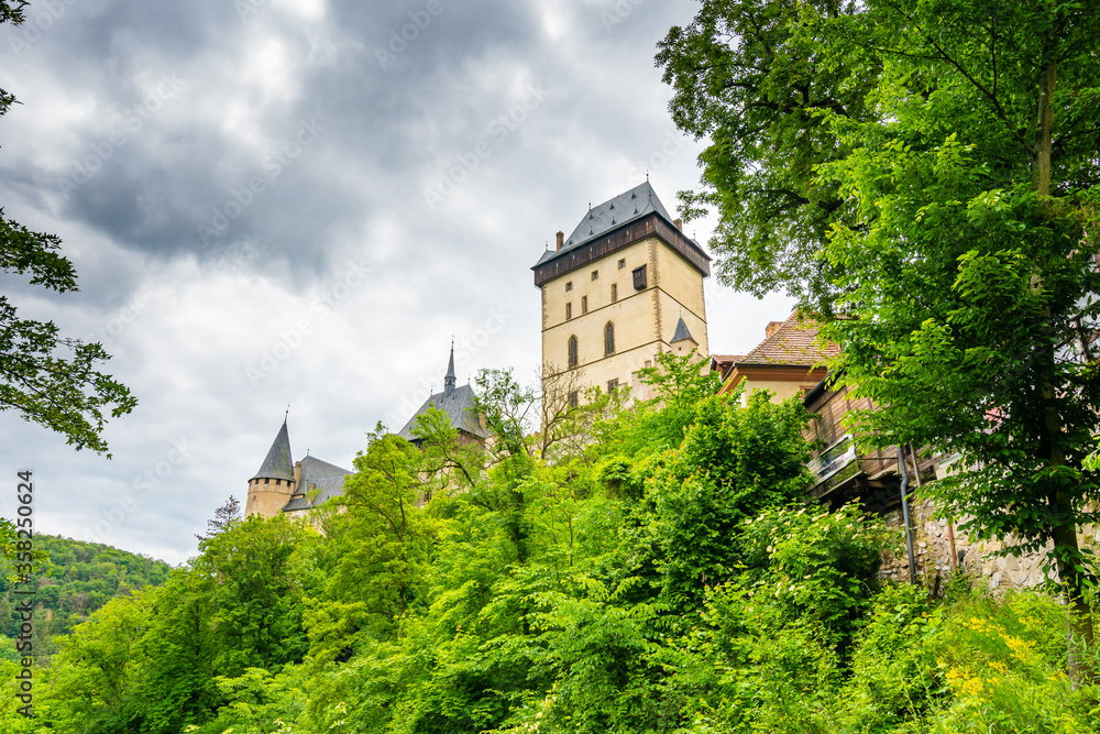Famous medieval gothic castle Karlstejn on top of the hill. Beautiful stronghold is built by king Charles IV. Historical national heritage of Czech Republic is placed near Prague city. Cloudy weather Famous medieval gothic castle Karlstejn on top of the hill. Beautiful stronghold is built by king Charles IV. Historical national heritage of Czech Republic is placed near Prague city. Cloudy weather