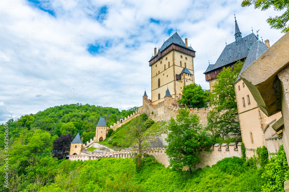 Famous medieval gothic castle Karlstejn on top of the hill. Beautiful stronghold is built by king Charles IV. Historical national heritage of Czech Republic is placed near Prague city. Cloudy weather