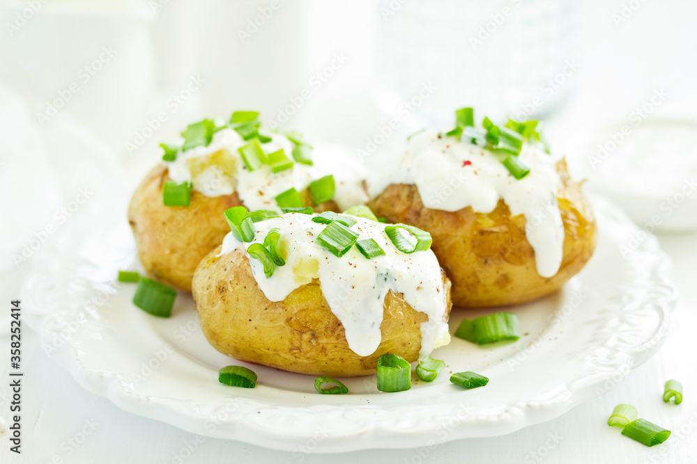 Baked potatoes with cheese, served with sour cream and onions. Selective focus Baked potatoes with cheese, served with sour cream and onions. Selective focus