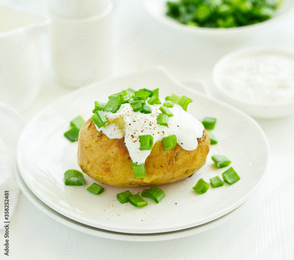 Baked potatoes with cheese, served with sour cream and onions. Selective focus Baked potatoes with cheese, served with sour cream and onions. Selective focus