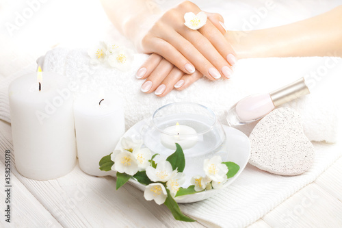 beautiful french manicure with jasmine, candle and towel on the white wooden table. spa