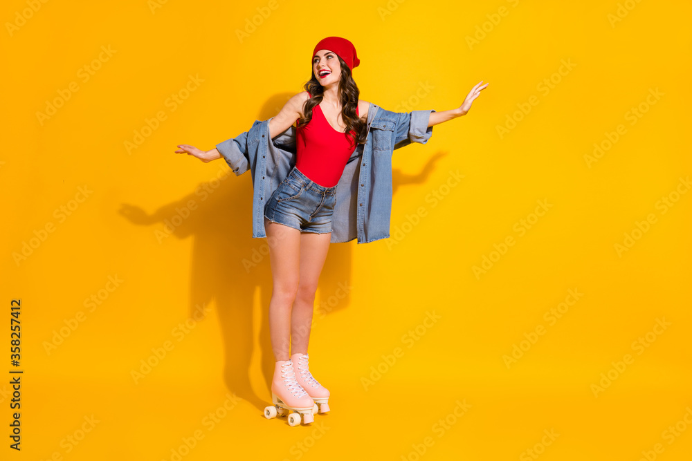 Full size photo of positive cheerful candid content teen girl ride roller skates with friend enjoy look copyspace wear red headwear singlet jeans isolated over bright color background