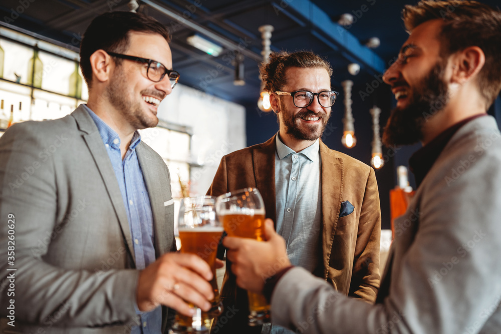 Business people drink beer after work in pub. Businessmen enjoy a beer. - obrazy, fototapety, plakaty 
