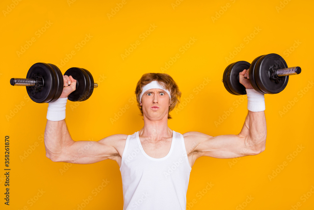Close-up portrait of his he nice attractive sportive funky muscular nerd guy sportsman lifting heavy barbell physical intense isolated over bright vivid shine vibrant yellow color background Close-up portrait of his he nice attractive sportive funky muscular nerd guy sportsman lifting heavy barbell physical intense isolated over bright vivid shine vibrant yellow color background