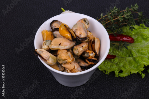 Pickled mussels in the bowl served pepper, garlic and salad