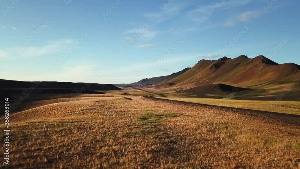 Sensational view of brown mountain countryside towards white car driving towards drone on back road of Iceland on sunny day, aerial approach Sensational view of brown mountain countryside towards white car driving towards drone on back road of Iceland on sunny day, aerial approach