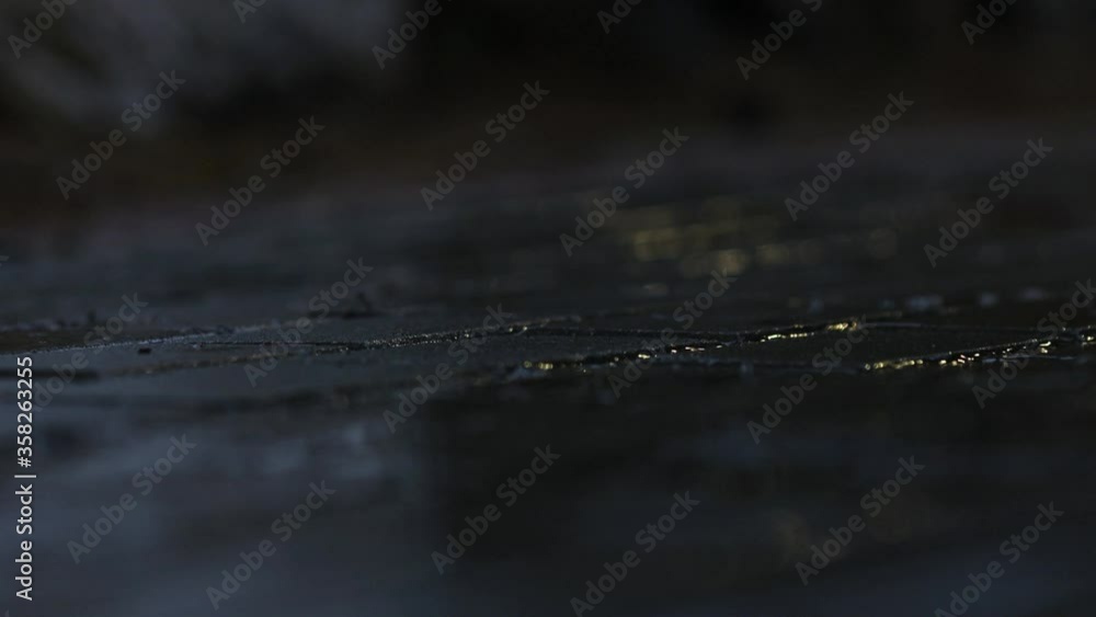 Dark rainy narrow stone walkway with view of person's shoes and pants walking by, static close up selective focus Dark rainy narrow stone walkway with view of person's shoes and pants walking by, static close up selective focus