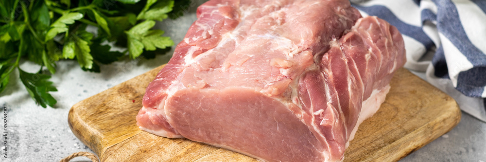 Raw pork carbonate on a white ceramic plate on the light gray kitchen table. Raw pork meat, tenderloin. Banner Raw pork carbonate on a white ceramic plate on the light gray kitchen table. Raw pork meat, tenderloin. Banner