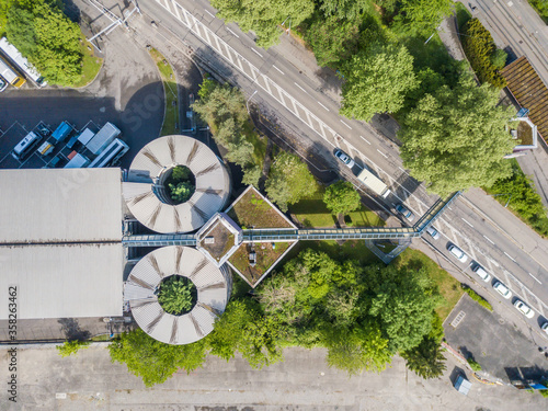 Aerial view of round geometric building with special shape in urban industrial area. Road near building.