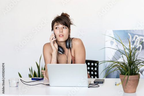 Young freelance woman working on the phone and laptop