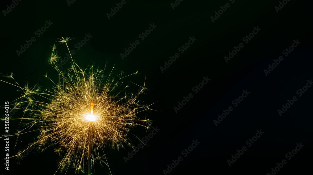 New Year single colored sparkling burning sparkler, salute on black background. Holiday concept background, copy space