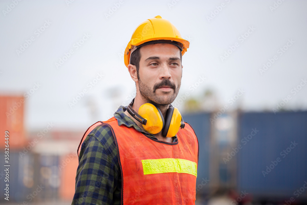 Engineer man in hardhat and safety vest, worker with protective headphones at construction site Engineer man in hardhat and safety vest, worker with protective headphones at construction site