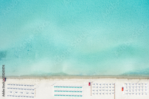 View from above, stunning aerial view of a white sand beach with beach umbrellas and a beautiful turquoise sea. Marinella Beach, Porto Rotondo,Sardinia, Italy.