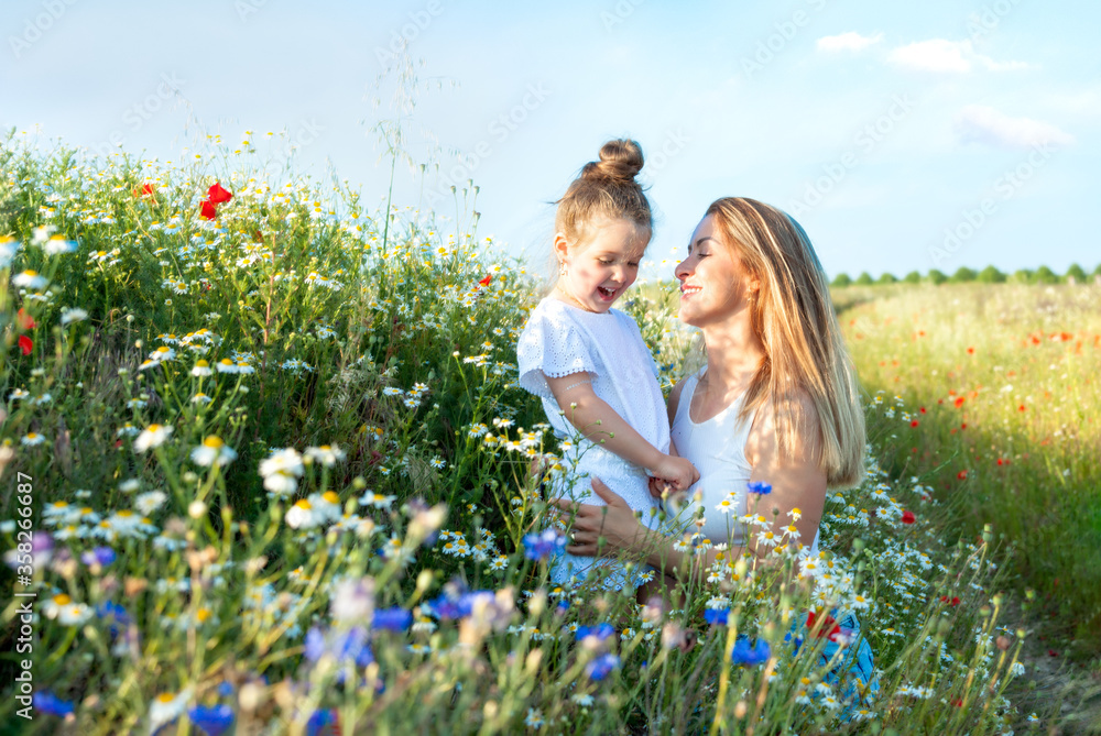 Fototapeta premium Mom and her pretty little daughter in a summer meadow