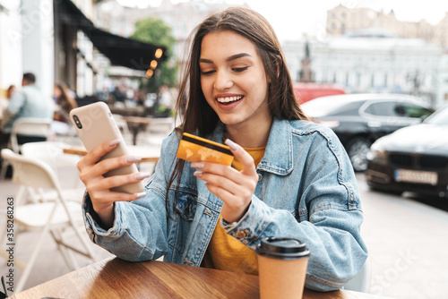 Image of smiling woman using cellphone and holding credit card photo