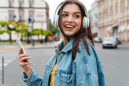 Schilderij op canvas Image of woman listening music with smartphone and wireless headphones