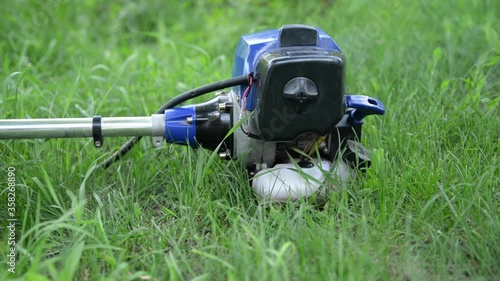 Running brushcutter trimmer on a green blurry background on a sunny summer day photo