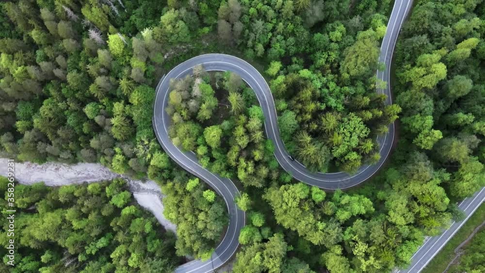 Aerial top down view of cars driving on a sinuous road through the woods in Germany