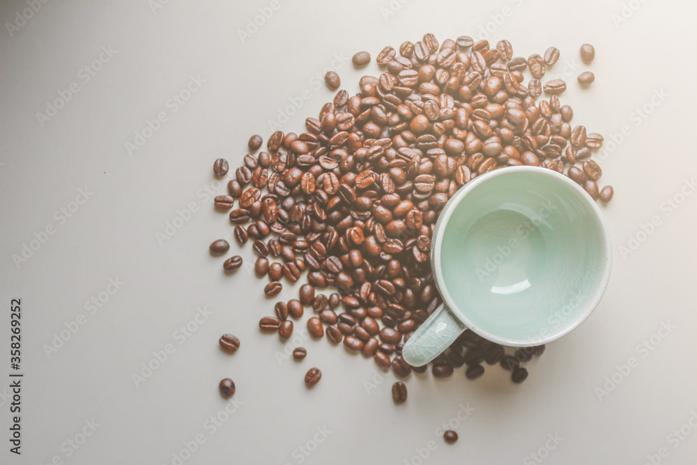 Naklejka premium The coffee cups and roasted coffee beans were placed on a white table by the window in the dining room, as the coffee beans were prepared for filming a drink menu. Top View and Copy Space