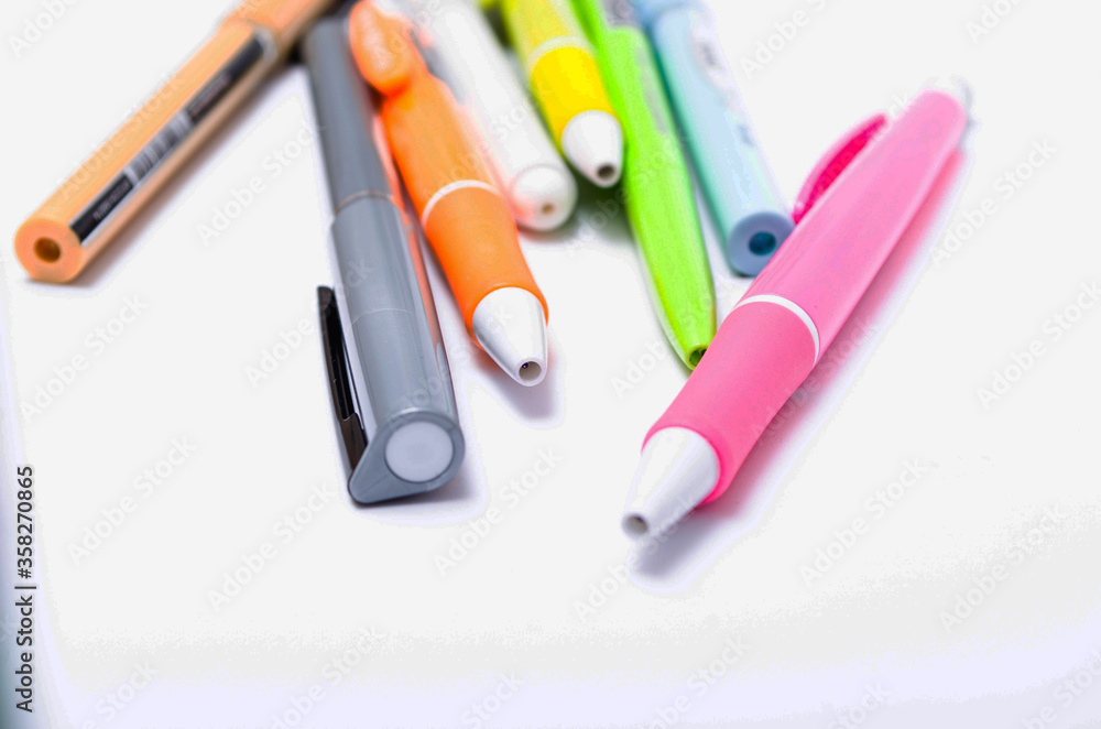 A large pile, the number of ballpoint pens of different colors on a white background. Pens for writing in close-up on a white background at an angle A large pile, the number of ballpoint pens of different colors on a white background. Pens for writing in close-up on a white background at an angle