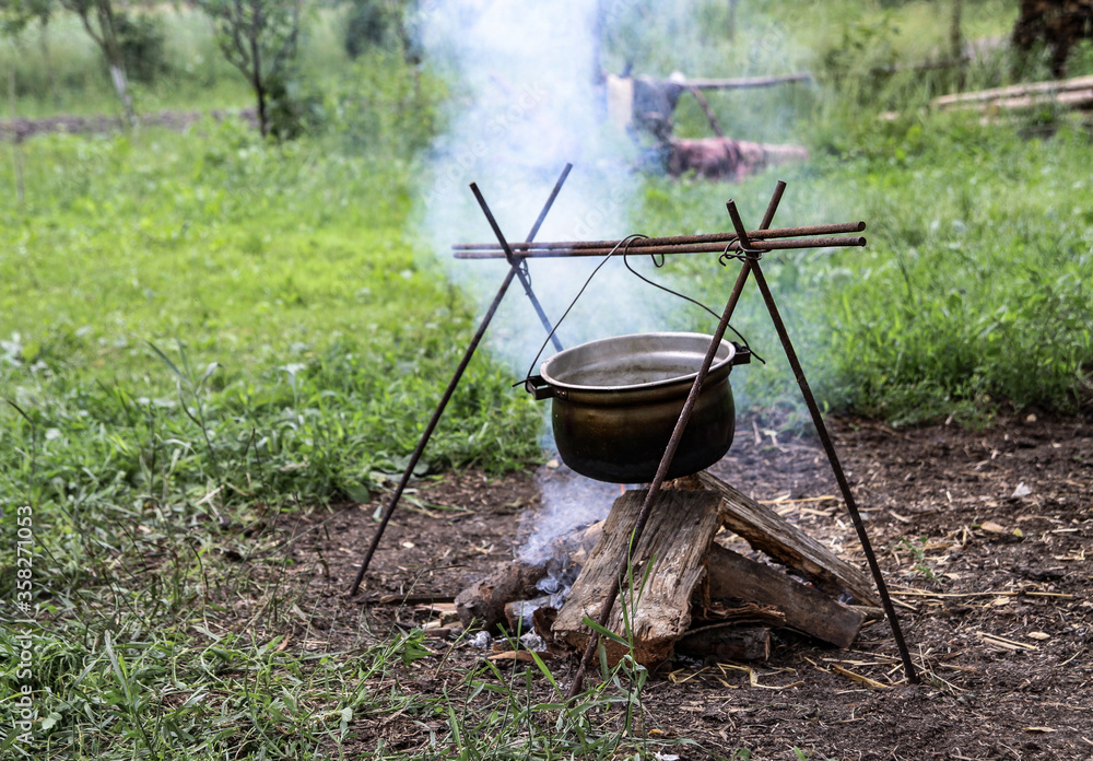 Bonfire and bowler on a background of nature. Summer camping in the park or outdoors Bonfire and bowler on a background of nature. Summer camping in the park or outdoors