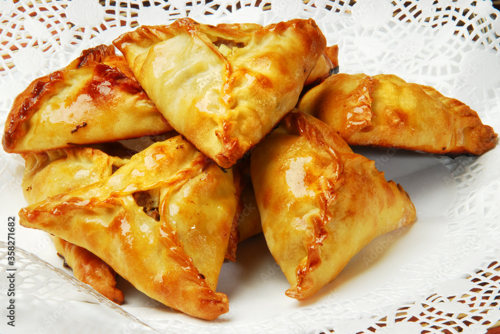 Group of individual pies with meat and potato - vak balish. Tatar traditional pies. Wooden background. Top view. Group of individual pies with meat and potato - vak balish. Tatar traditional pies. Wooden background. Top view.