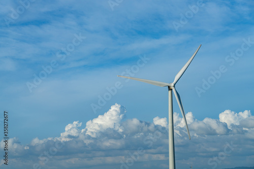 Close-up wind turbines or wind energy converter in sunny day with blue sky and white clouds