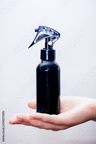 the black spray gun is held in the hand on a light backgroun
