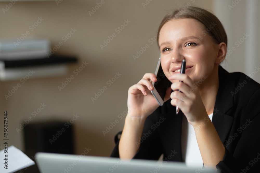 beautiful caucasian woman talking on the phone and smiling. Workplace at home. Remote work during a pandemic. beautiful caucasian woman talking on the phone and smiling. Workplace at home. Remote work during a pandemic.