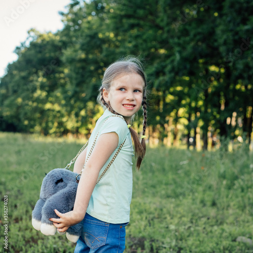 A girl of European appearance with two pigtails and a backpack looks away